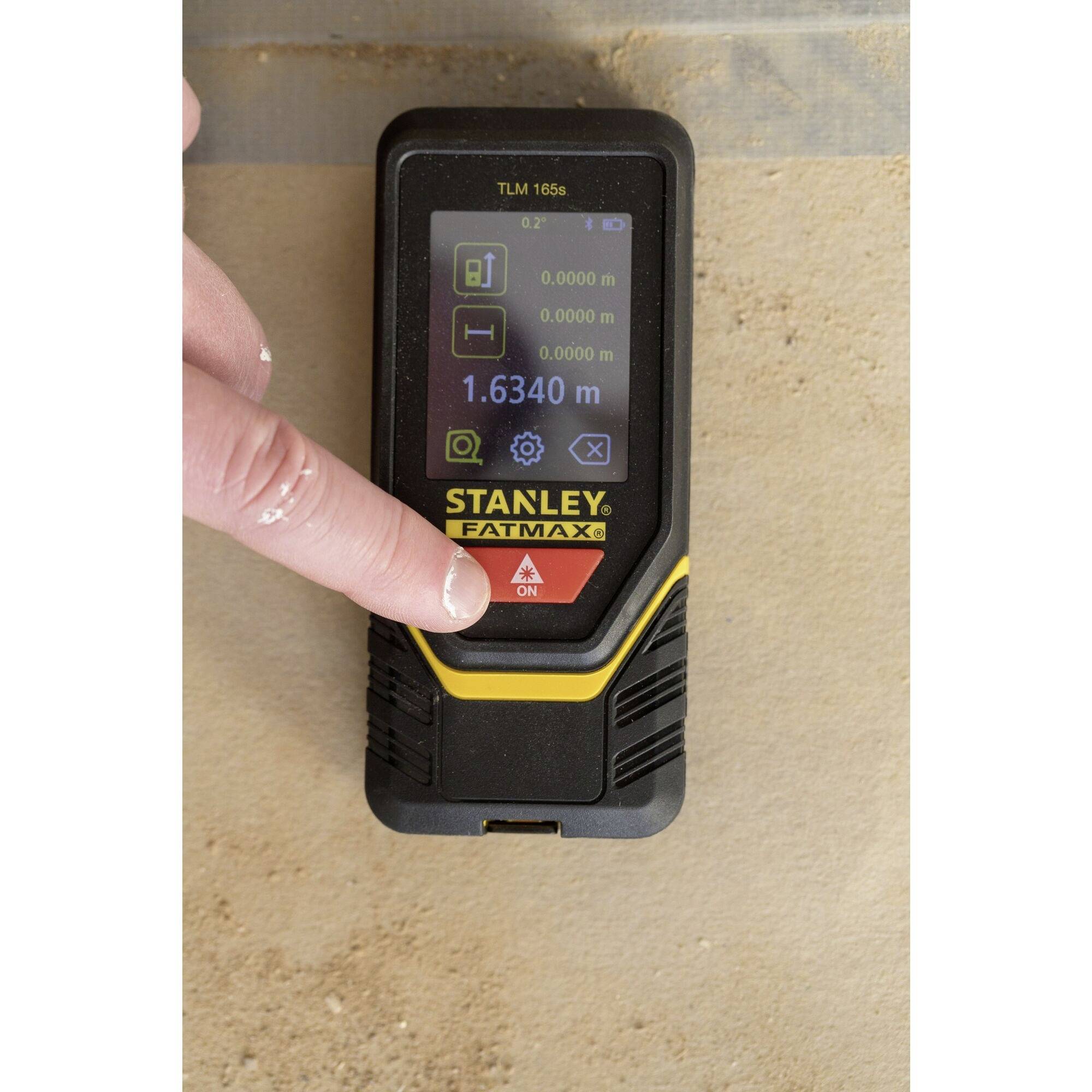 'Miernik laserowy marki Stanley jest obsługiwany jednym palcem. Urządzenie wyświetla pomiar 1,6340 m.'