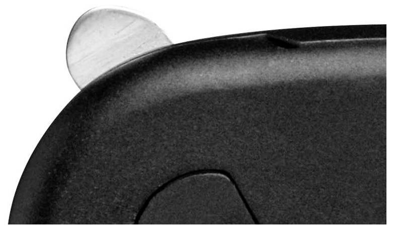 Zbliżenie przedstawia róg ciemnoszarej obudowy z srebrnym przyciskiem lub dźwignią na krawędzi.