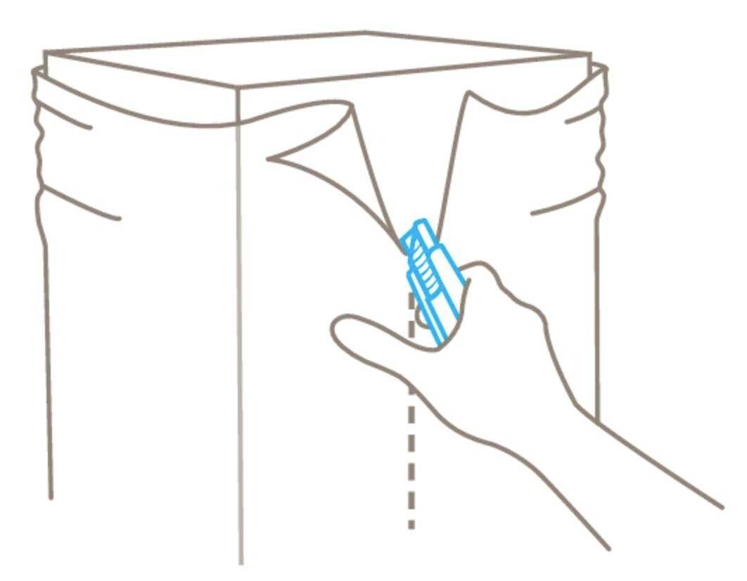 Ręka używa noża do rozcinania kartonu wzdłuż linii przerywanych.