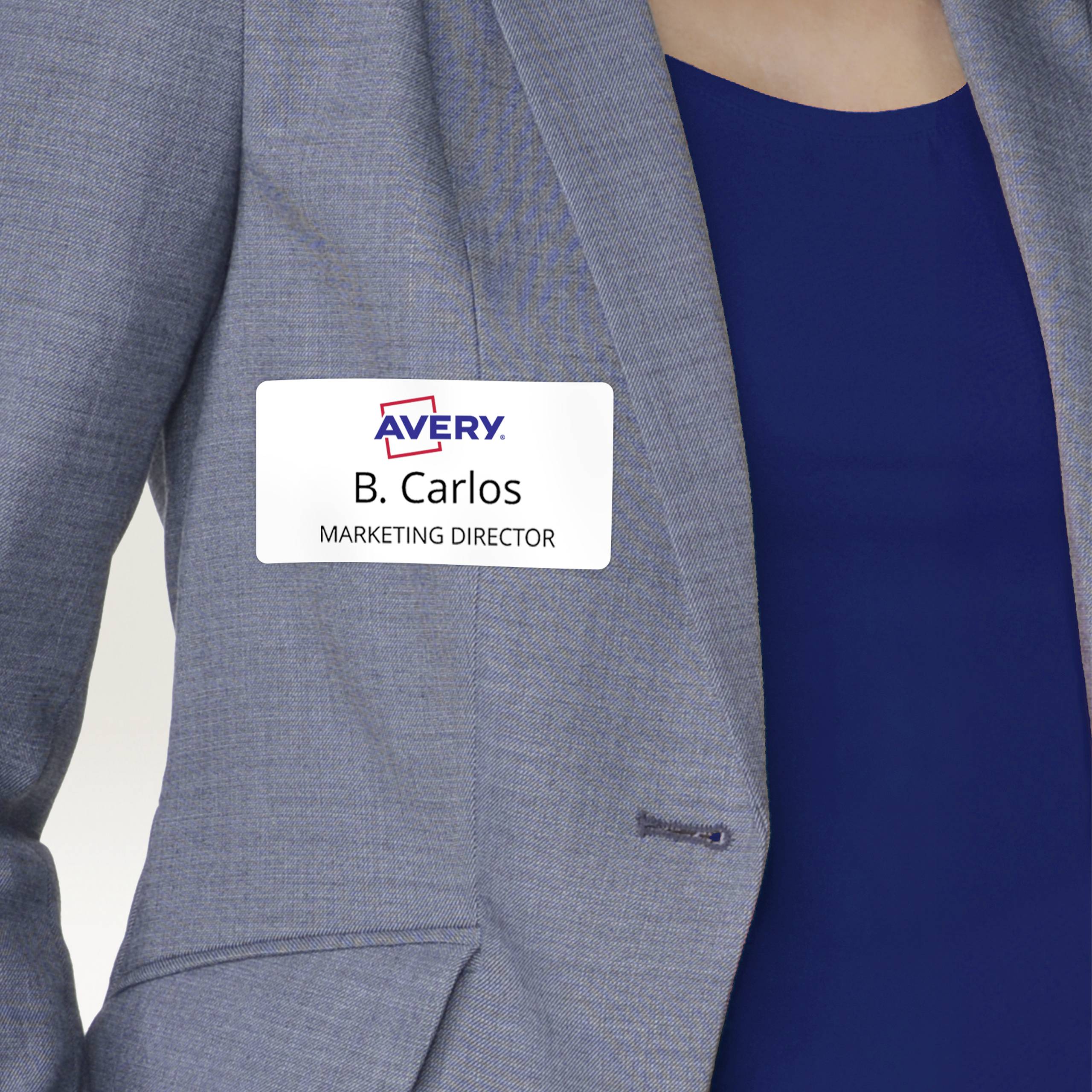 Osoba nosi identyfikator z napisem 'B. Carlos, Dyrektor ds. Marketingu' na szarym żakiecie.