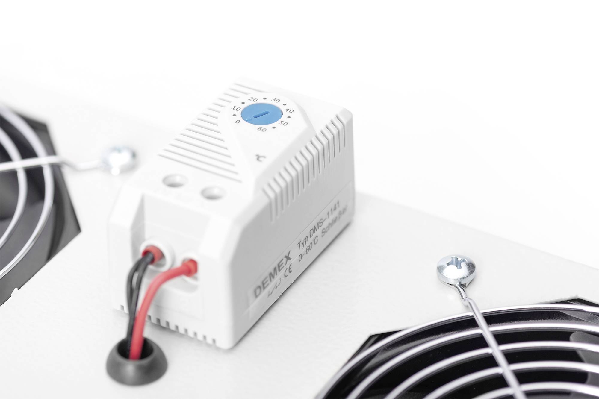 Elektroniczne urządzenie z pokrętłem regulacji temperatury, zamontowane na białej powierzchni obok kratek wentylacyjnych.