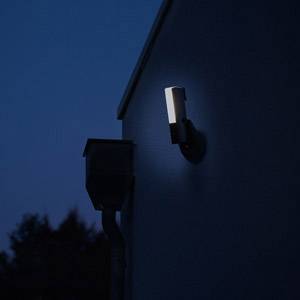 Oświetlenie elewacji budynku o zmierzchu, otoczone ciemnymi drzewami w tle.