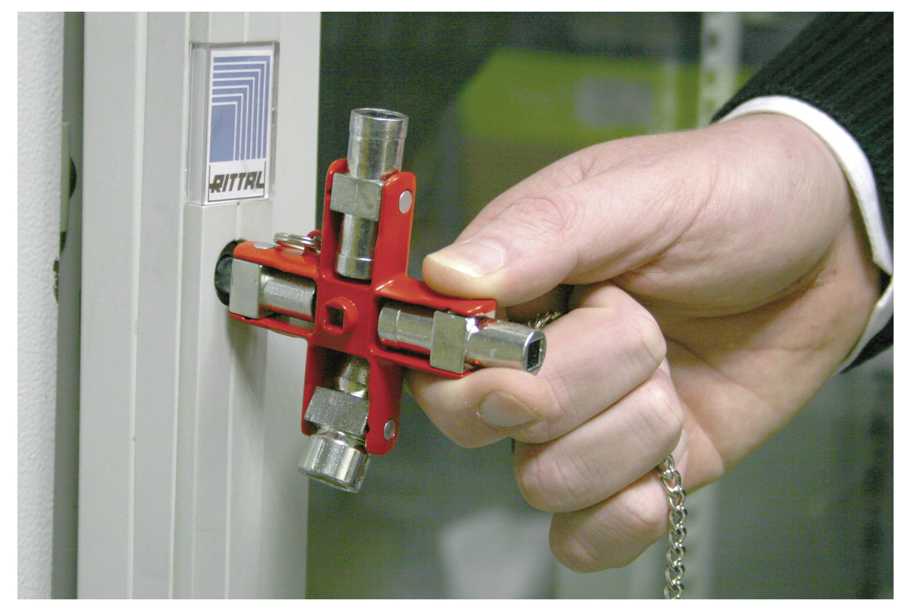 Osoba używa wielofunkcyjnego czerwonego metalowego narzędzia do otwarcia zamkniętej szafki, prezentując jego przydatność podczas prac konserwacyjnych lub zadań związanych z bezpieczeństwem.