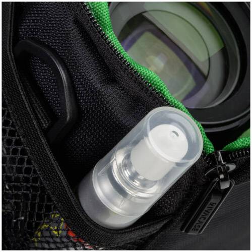 Mała butelka z rozpylaczem i soczewka obiektywu w torbie z zielonym zamkiem błyskawicznym i siateczkową kieszenią.