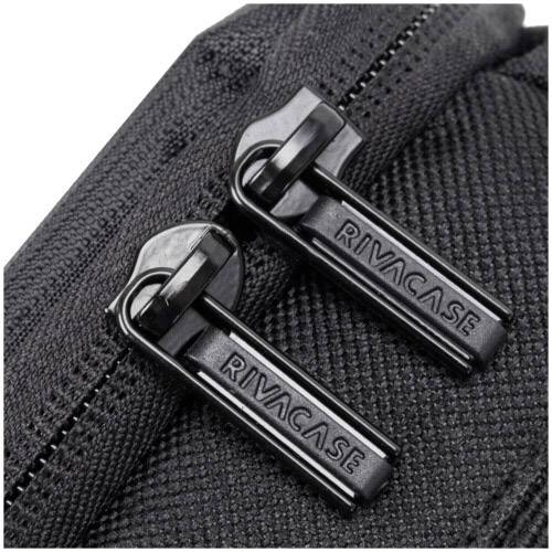 Zbliżenie dwóch czarnych suwaczków zamka błyskawicznego na torbie z napisem 'RIVACASE'.