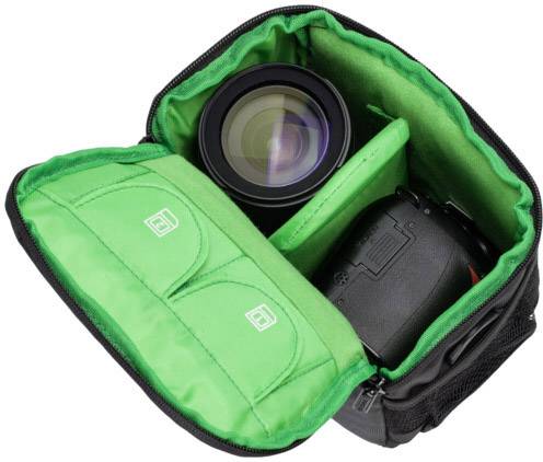 Aparat cyfrowy w czarno-zielonej torbie, otwarty, ukazujący obiektyw i korpus aparatu.
