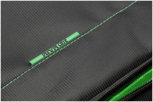 Zbliżenie czarnej, teksturowanej torby z zielonym zamkiem błyskawicznym i zieloną szwą. Nazwa marki 'RIVACASE' jest wytłoczona.