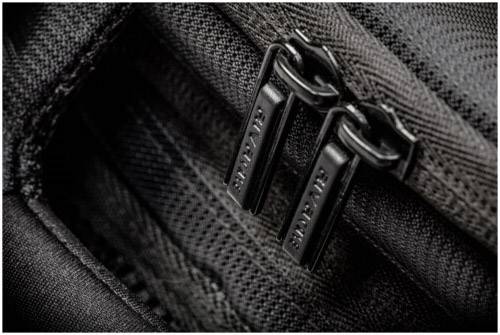 Zbliżenie dwóch czarnych metalowych zamków błyskawicznych na ciemnoszarej torbie z tkaniny.