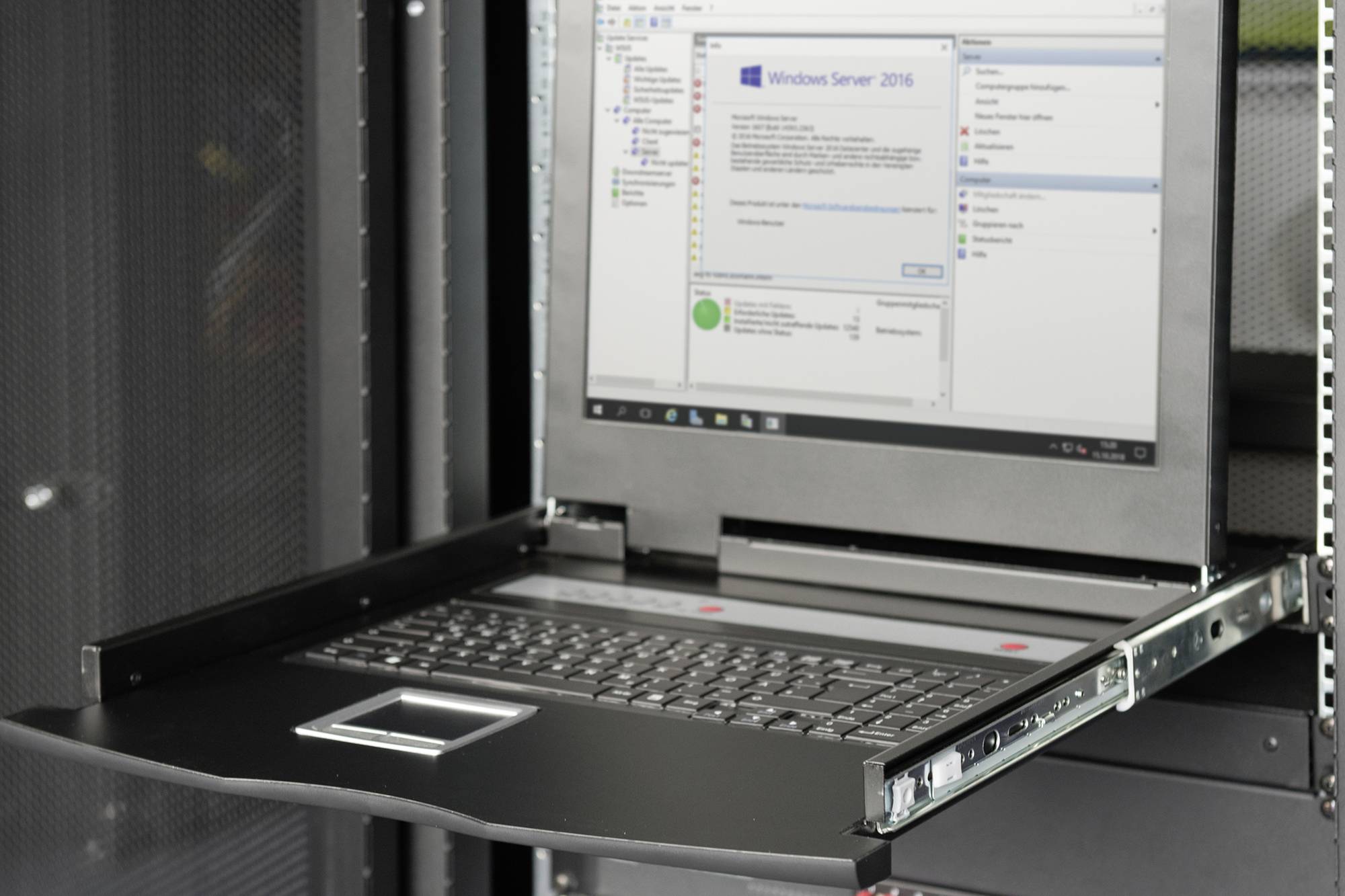 Szafa serwerowa z wysuwanym ekranem i klawiaturą, wyświetlająca instalację Windows Server 2016, w centrum informatycznym.