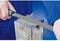 Osoba pilnikiem wygładza krawędź bloku metalowego.