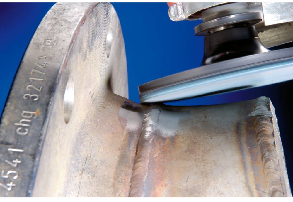 Urządzenie szlifierskie obrabia krawędź metalową. Widoczne są iskry oraz gładka powierzchnia po szlifowaniu. Bliski kadr koncentrujący się na narzędziu.