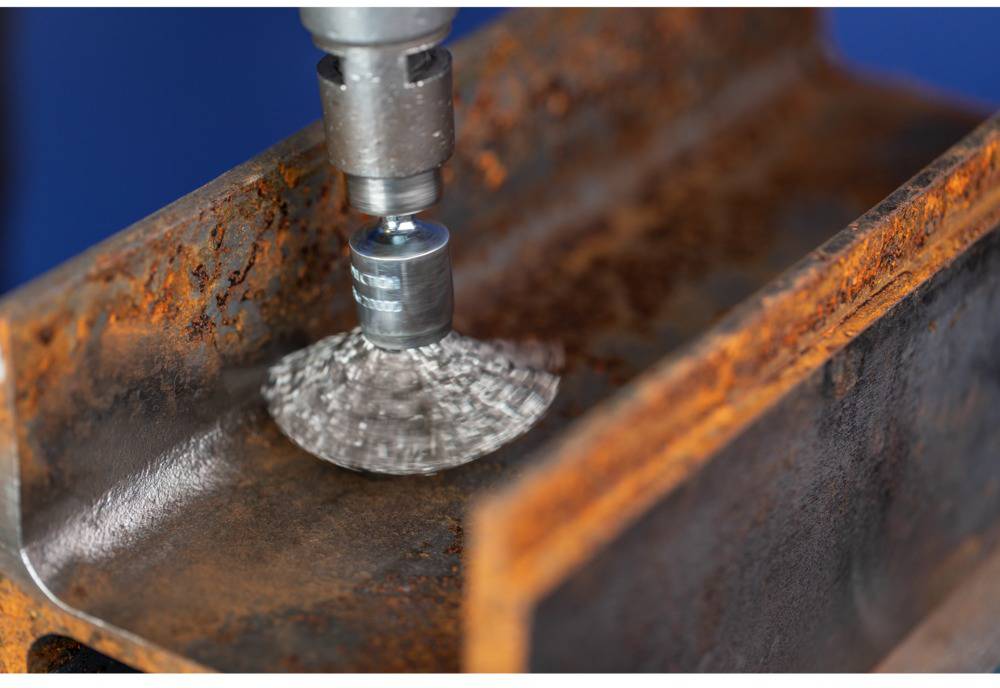 Szlifierka kątowa obrabia zardzewiały element metalowy. Lecą iskry, a metal jest polerowany, aby usunąć rdzę.