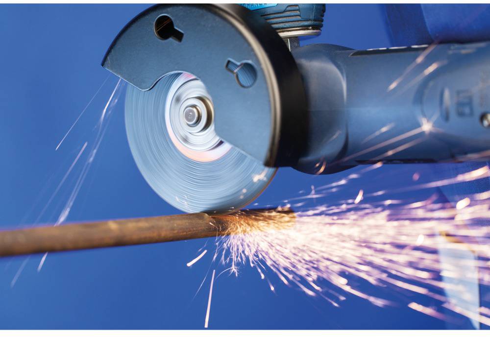 Szlifierka wyrzucająca iskry podczas cięcia metalowej rury. Obraz ukazuje dynamikę iskier i niebieską maszynę.