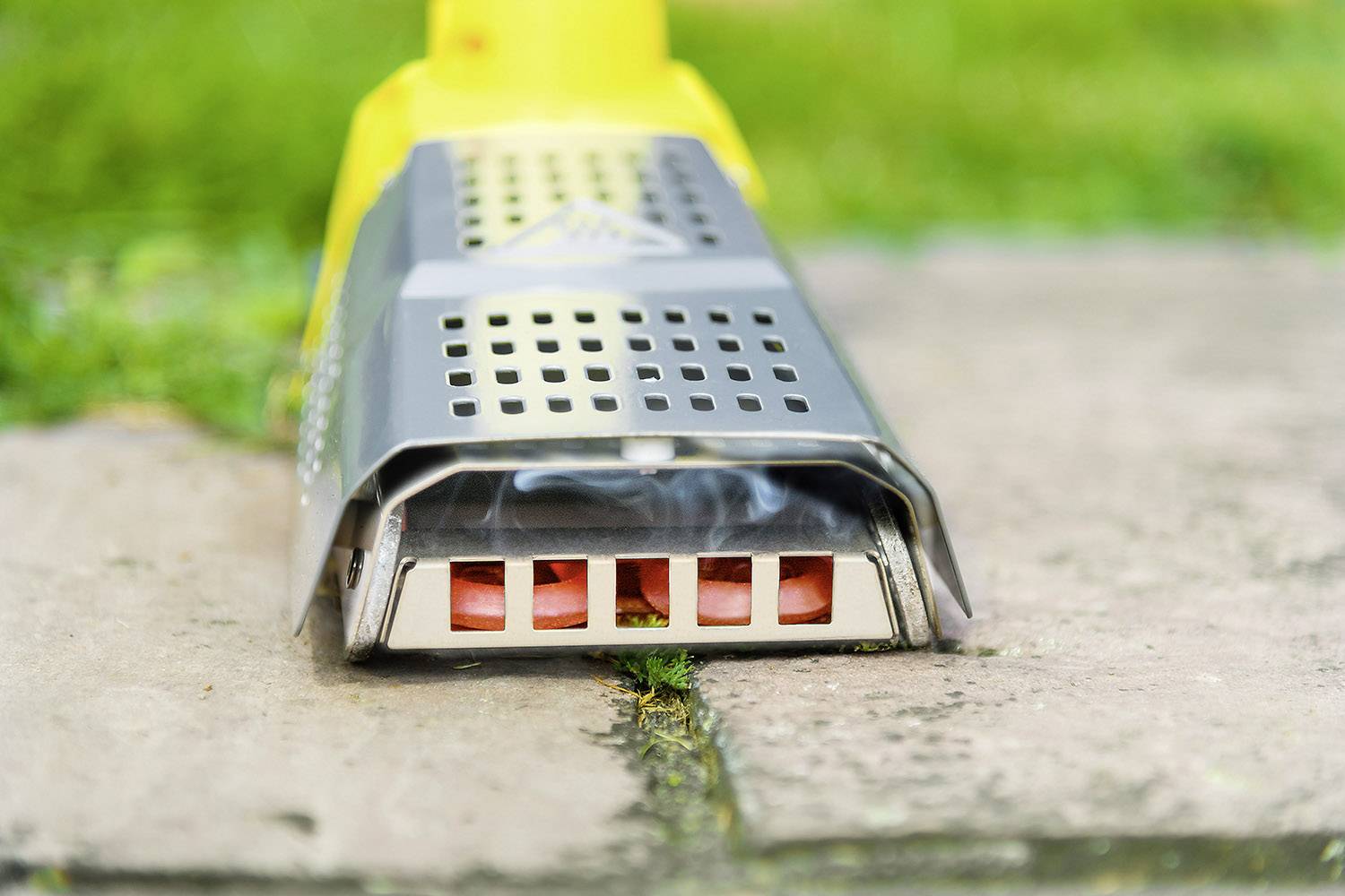 Żółte urządzenie do zwalczania chwastów nagrzewa na wolnym powietrzu chodnik, aby usunąć chwasty rosnące między kostkami brukowanymi.