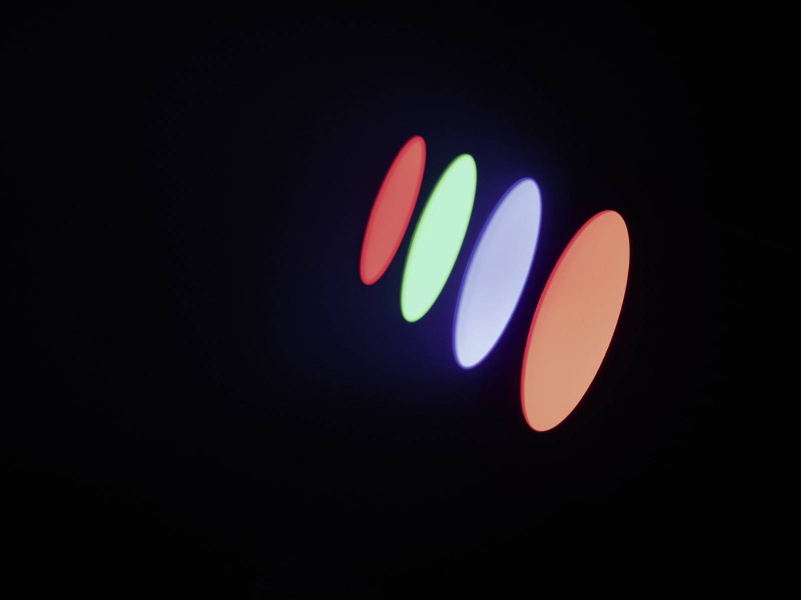 Kolorowo podświetlone eliptyczne kształty unoszą się na czarnym tle, składające się z linii w kolorach czerwonym, zielonym, niebieskim i pomarańczowym.