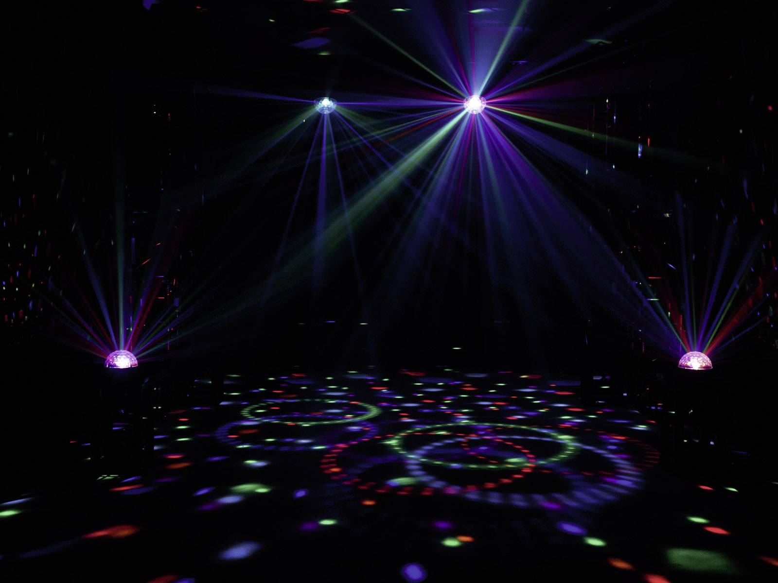 Kolorowe światła dyskotekowe rzucają kręgi i wzory na podłogę w ciemnym pomieszczeniu, tworząc żywiołową atmosferę imprezy.