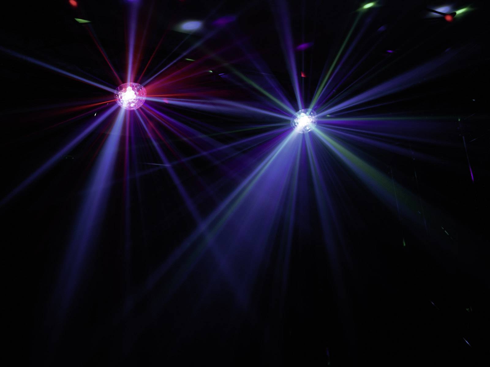 Dwa kolorowe reflektory emitują wiązki światła w ciemnym pokoju. Pokaz świetlny z czerwonymi, niebieskimi i zielonymi promieniami.