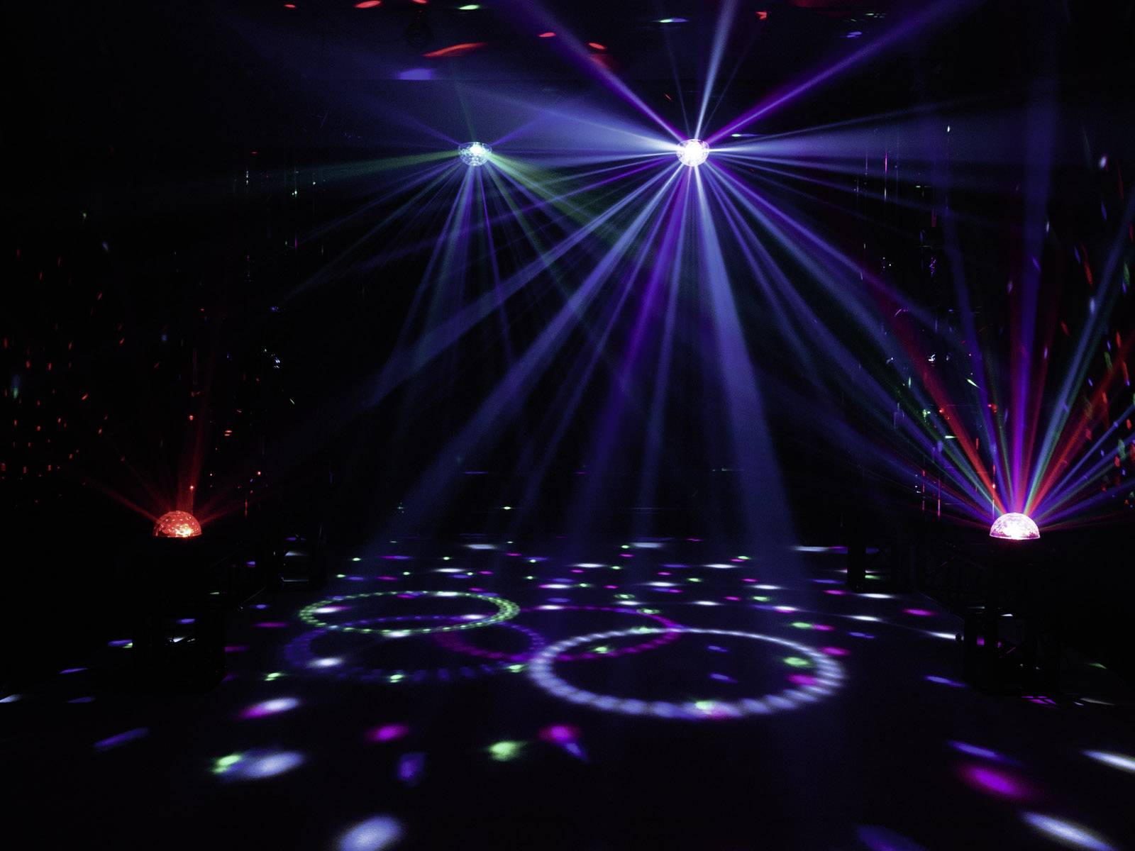 Kolorowe światła i wiązki laserowe oświetlają ciemną scenę, tworząc dynamiczną i nastrojową atmosferę wydarzenia.