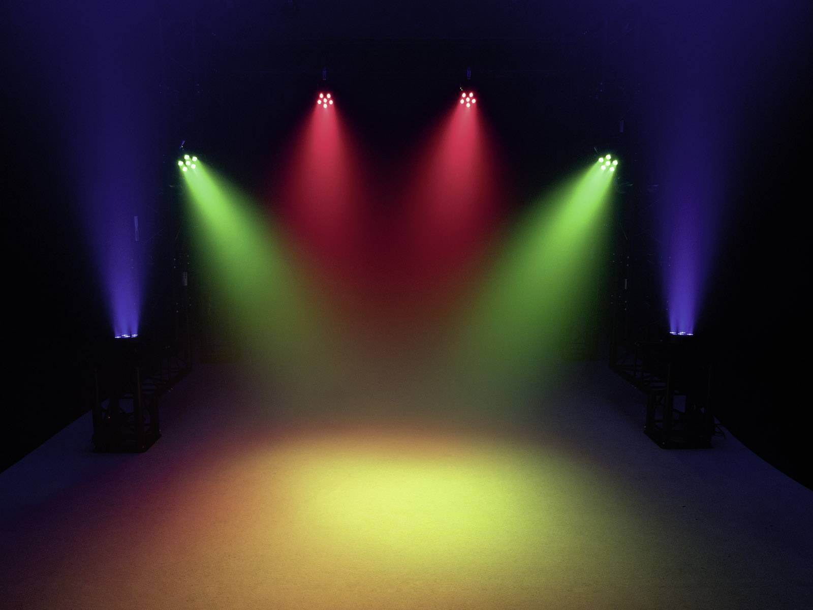 Scena z kolorowymi reflektorami w kolorach niebieskim, czerwonym i zielonym, które oświetlają pustą przestrzeń. Razem tworzą one kolorowy wzór świetlny.