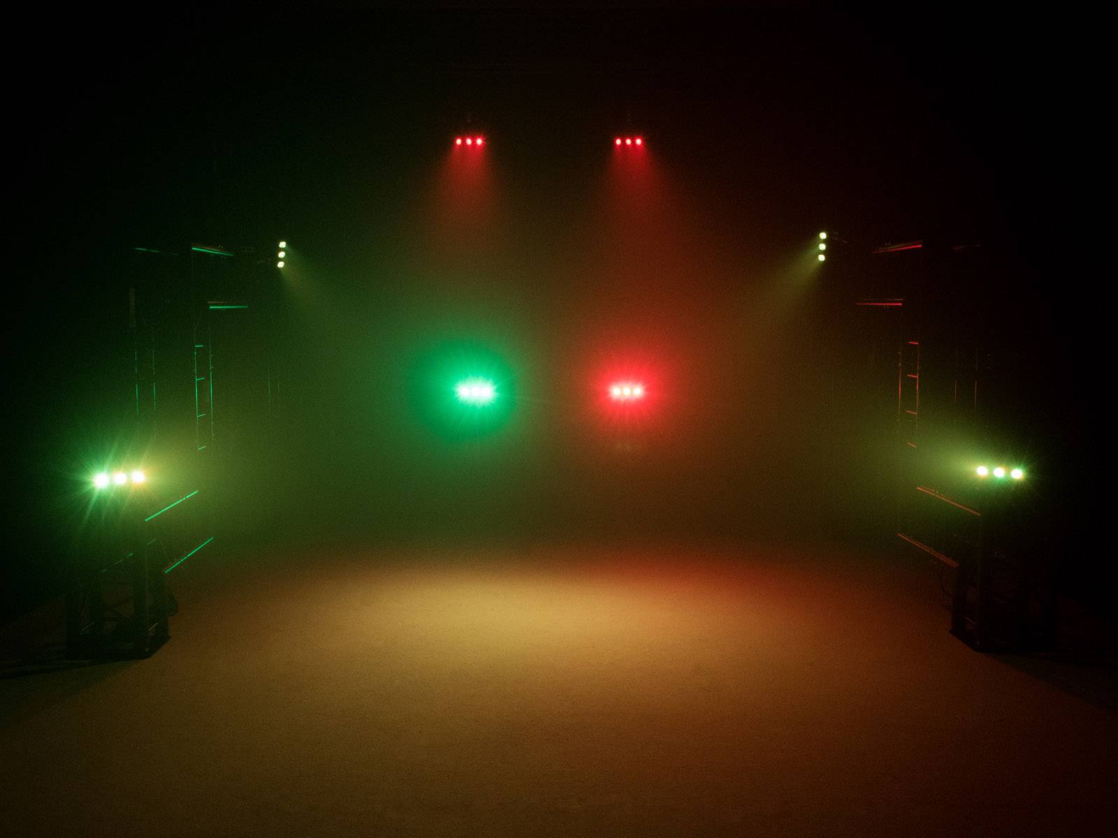 Scena oświetlona czerwonym i zielonym światłem, które rozświetla mgłę, bez widocznych osób lub obiektów.