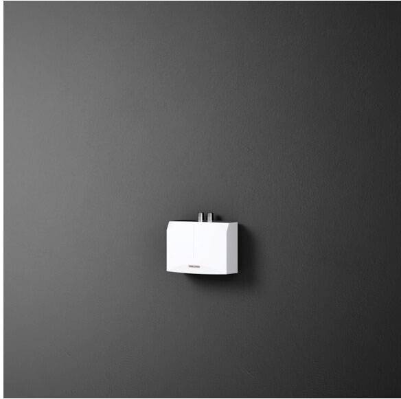 Na ciemnoszarej ścianie wisi mały, biały, prostokątny bojler.