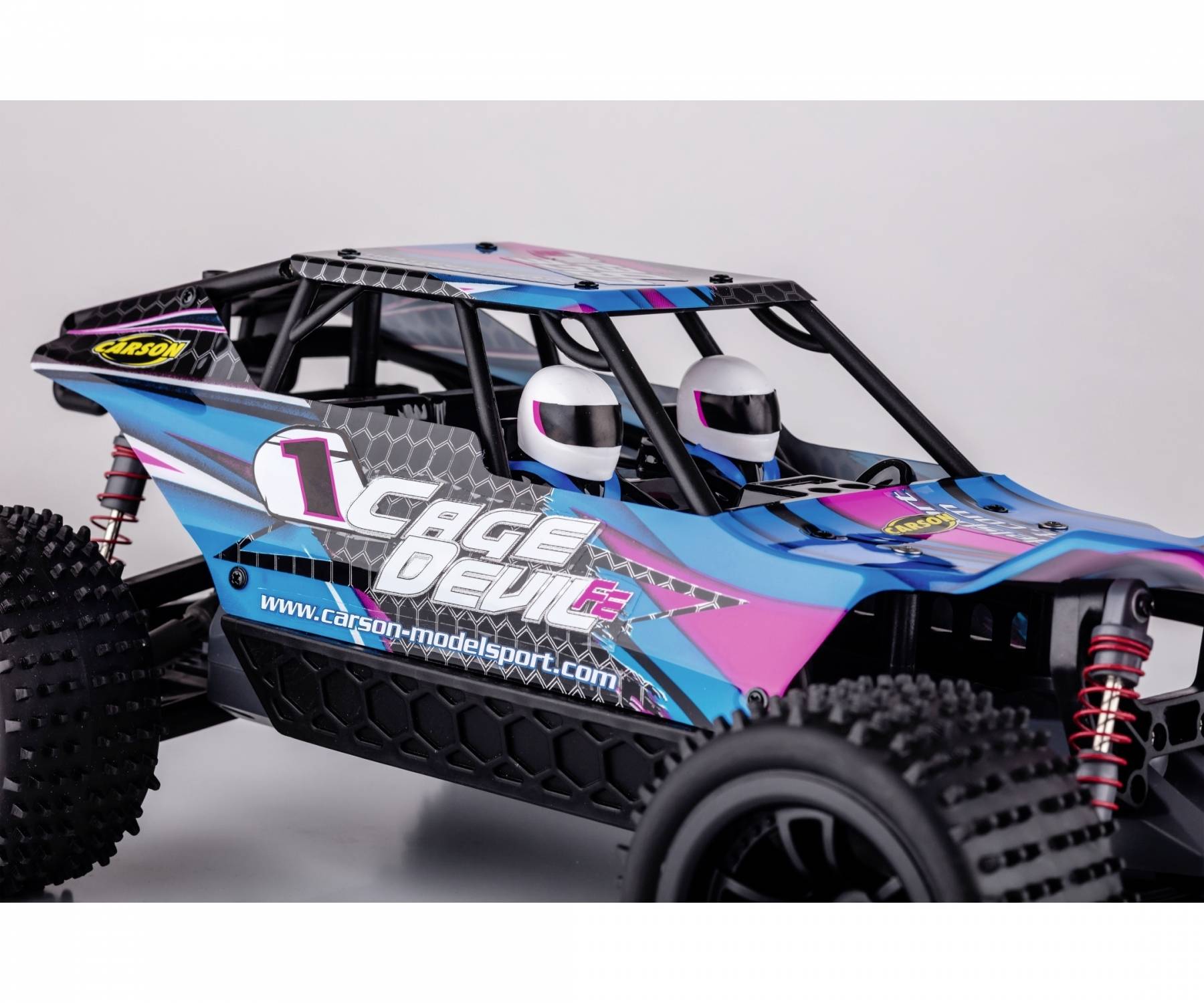 Zdalnie sterowany samochód modelarski w niebiesko-różowym designie, z dwoma hełmami w środku, napisem 'Cage Devil' i solidnymi oponami.