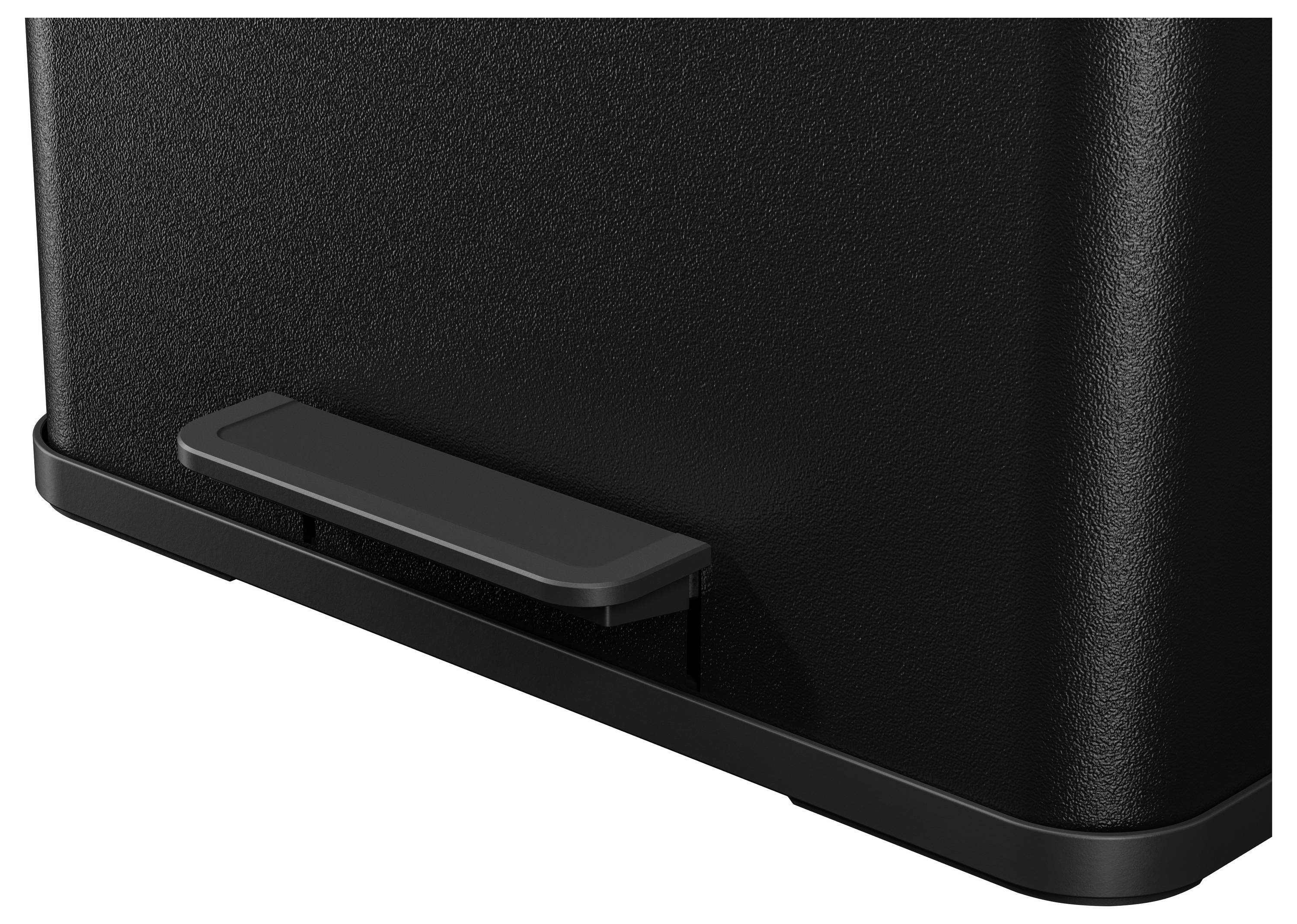 Czarny obiekt z prostokątną płytą pedałową od spodu, prawdopodobnie część większego urządzenia lub maszyny.