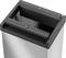 Szary kosz na śmieci z prostokątnym otworem i widocznym zawiasem u góry; odpowiedni do nowoczesnych biur lub kuchni.