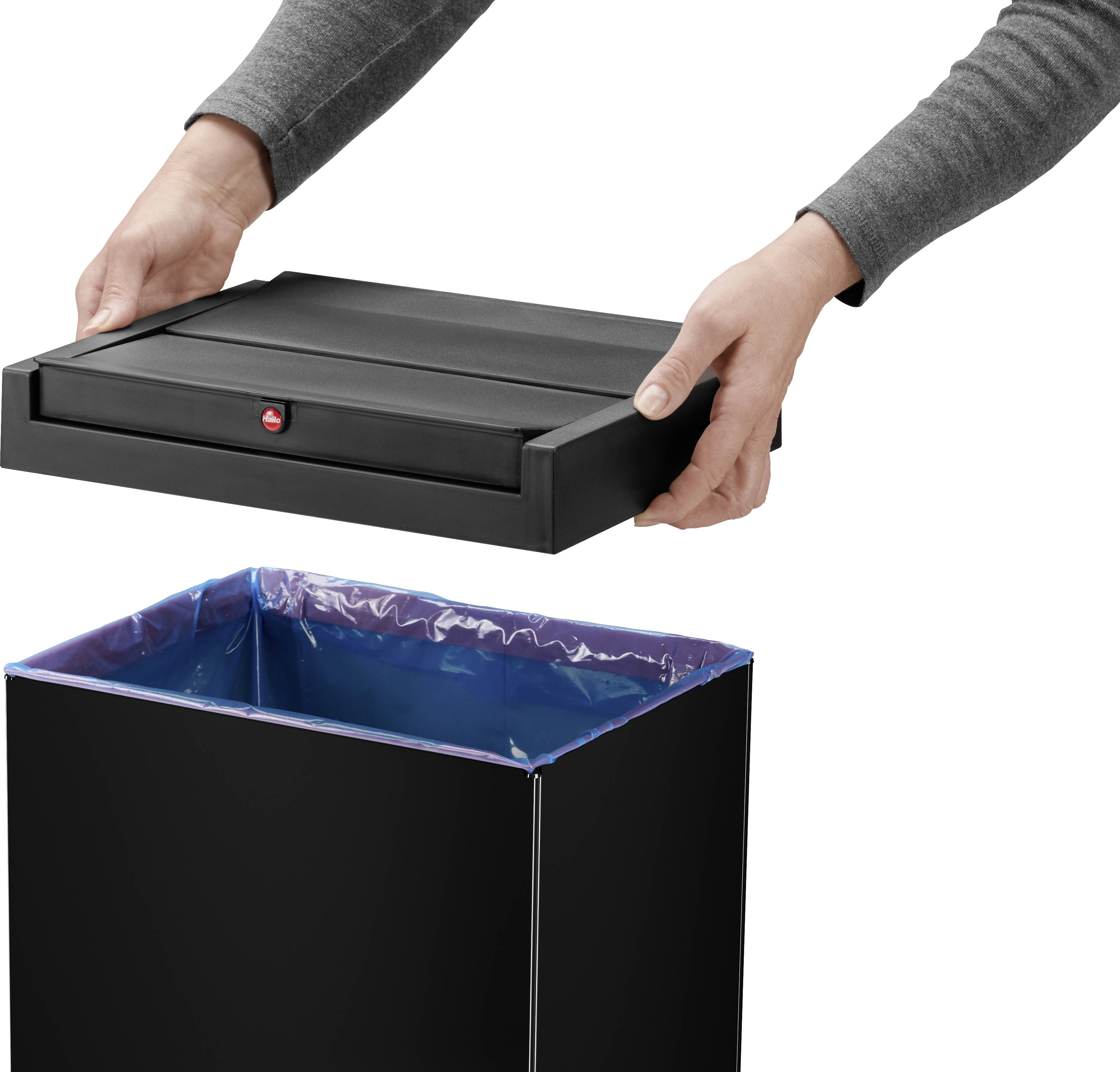 Osoba zdejmuje pokrywę czarnego kosza na śmieci. Kosz zawiera niebieski worek na śmieci.