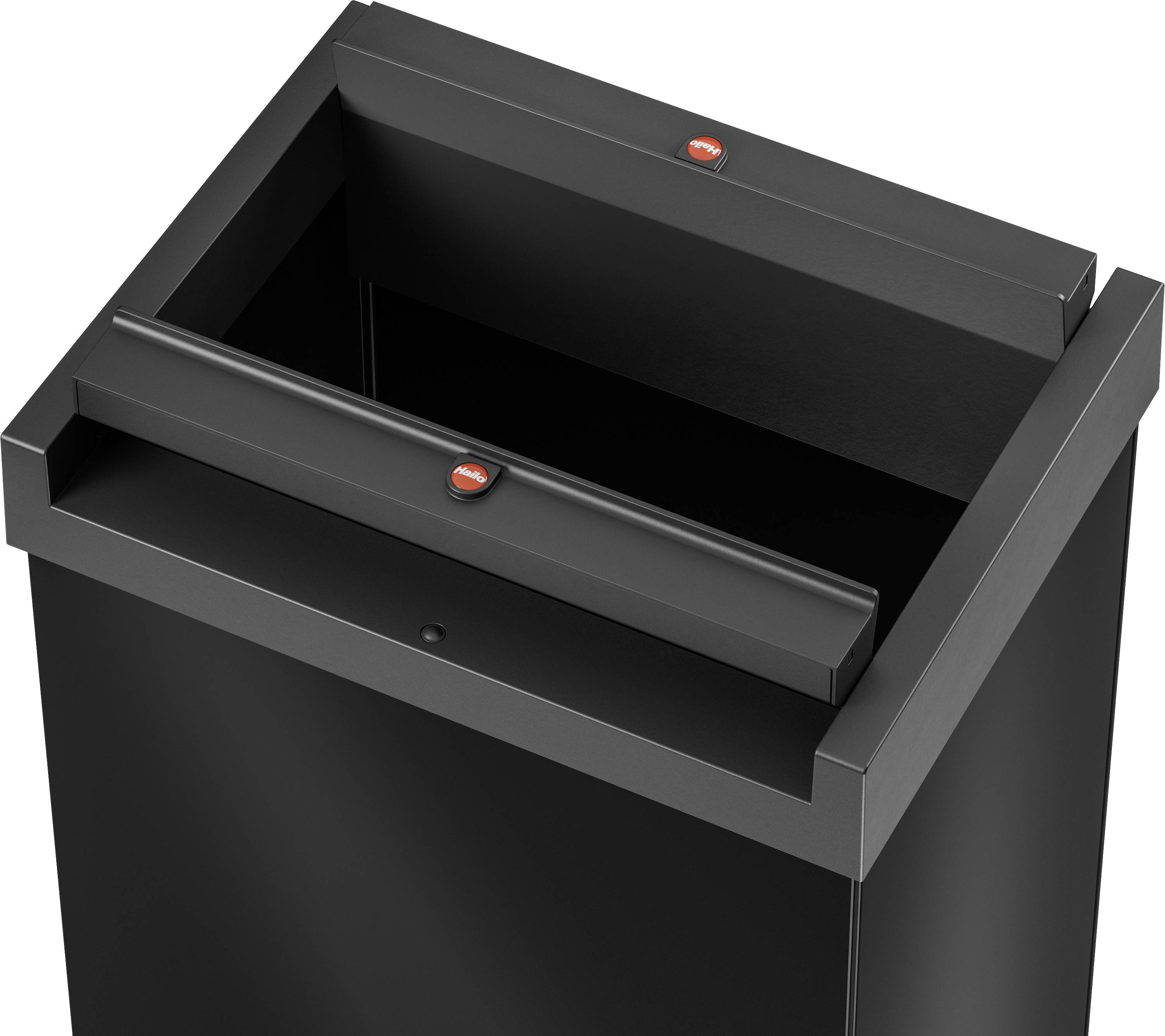 Czarny, otwarty kosz na śmieci z pokrywą, przeznaczony do użytku wewnętrznego. Pokrywa posiada małe czerwone naklejki jako wskazówki.