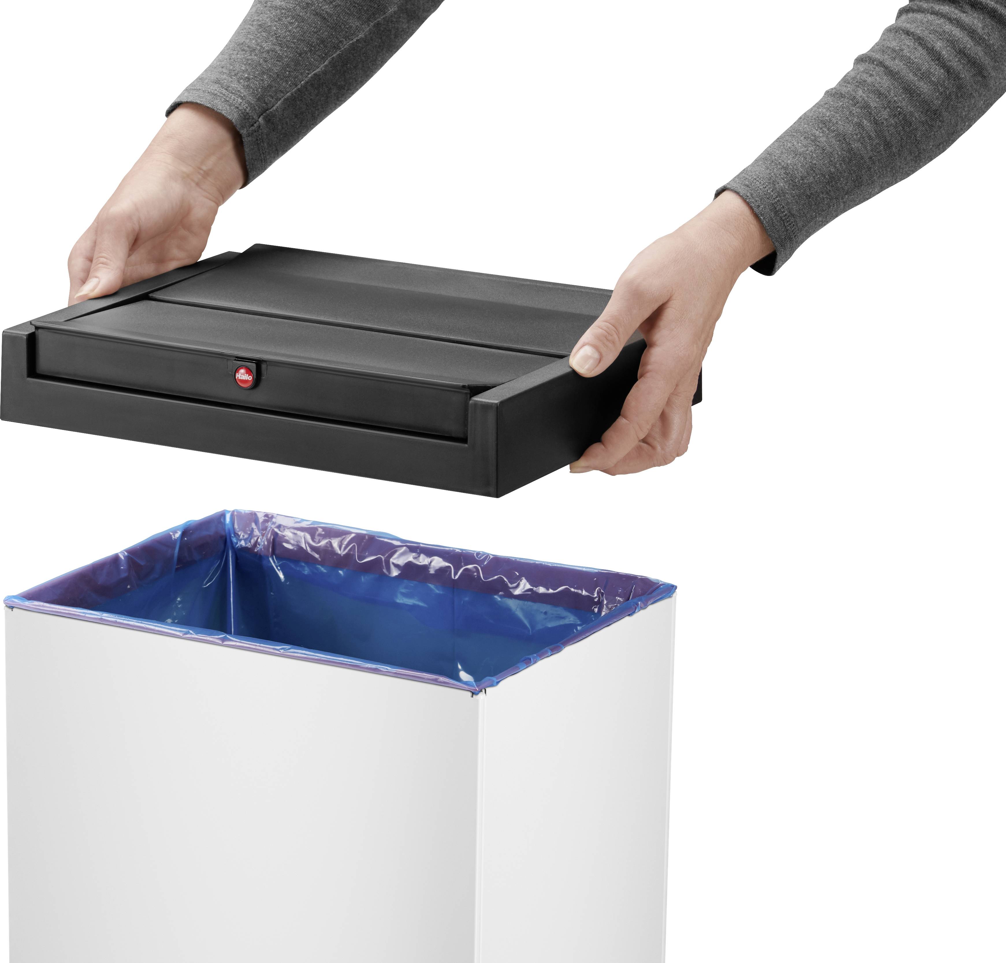 Osoba zdejmuje czarną pokrywę z białego kosza na śmieci. Wnętrze kosza wyłożone jest niebieską folią z tworzywa sztucznego.