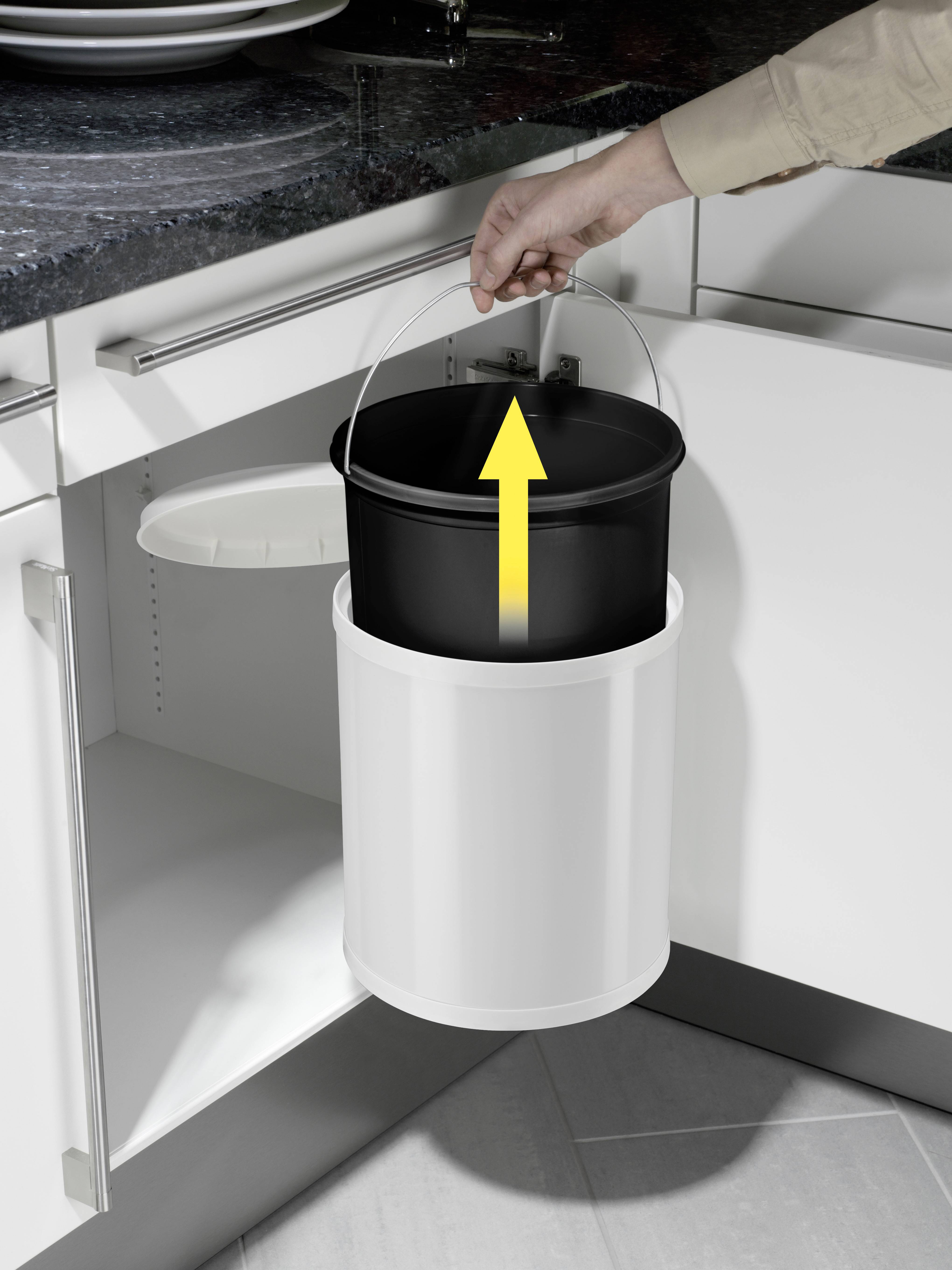 'Wiadro zostaje podniesione z białego kosza na śmieci pod zlewem. Ręka trzyma uchwyt czarnego wewnętrznego wiadra.'
