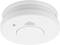 Biały czujnik dymu zamontowany na suficie. Posiada centralny przycisk i małą diodę LED.