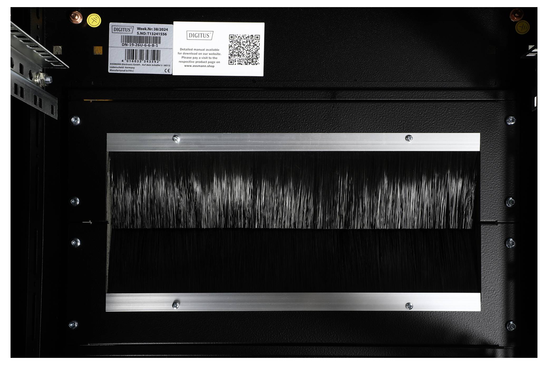 Czarny prostokąt z pionowymi włoskami, oprawiony w metalową ramkę, wewnątrz obudowy komputera.