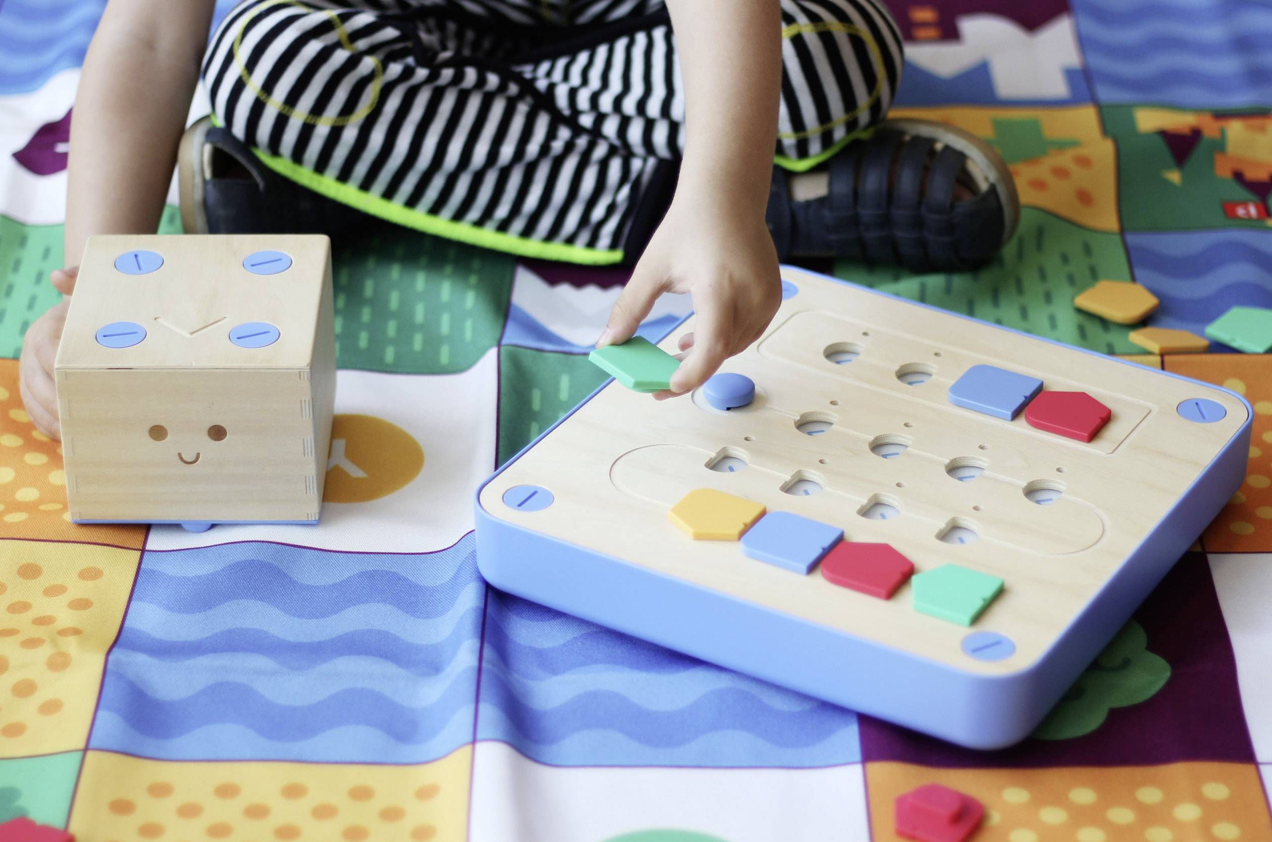 Dziecko bawi się kolorową zabawką edukacyjną na macie puzzlowej, poznając kształty i kolory.