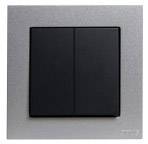 Elegancki, nowoczesny włącznik światła z dwiema czarnymi dźwigniami na srebrnej płytce, idealnie komponujący się z współczesnymi wnętrzami.