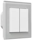 Podwójny przełącznik świetlny w kolorze białym o prostokątnym kształcie zamontowany na szarej płycie.
