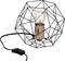 Nowoczesna lampa stołowa z geometryczną czarną metalową ramą, widoczną żarówką i miedzianą podstawą, podłączona przewodem elektrycznym.