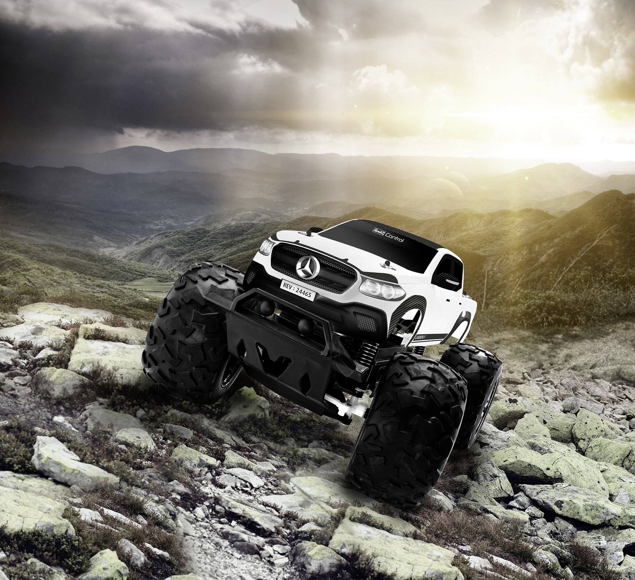 Zdalnie sterowany biały monster truck zabawka przemierza trudny, skalisty teren o zachodzie słońca, na tle groźnego nieba.