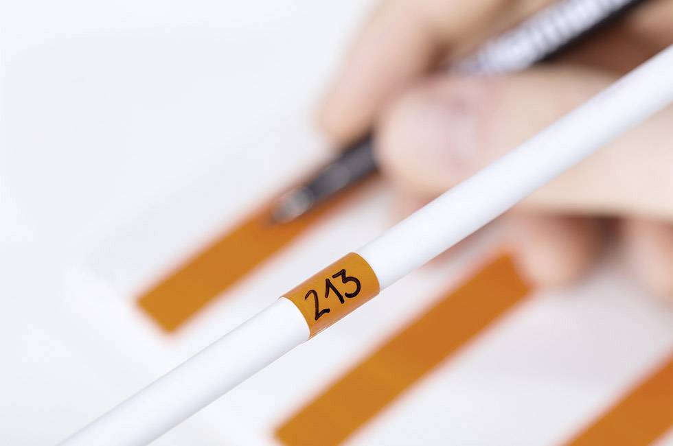 Zbliżenie kartki z numerem '213' na tle pomarańczowych pasów, ręcznie pisane notatki w tle.