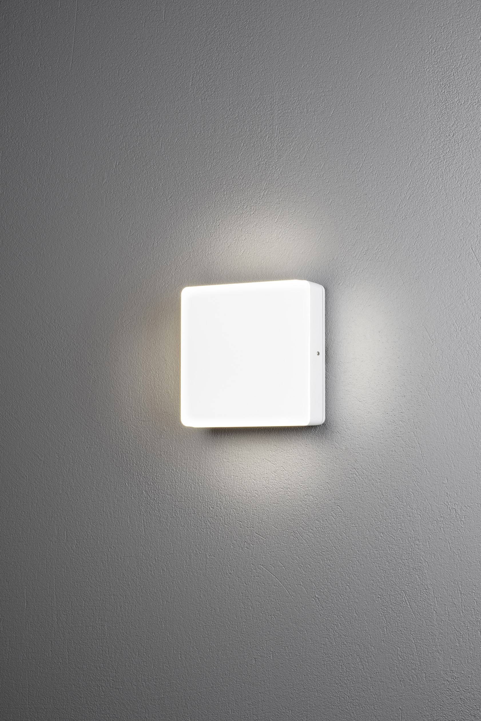 Biała, kwadratowa lampa ścienna na szarej ścianie, emitująca delikatne światło; nowoczesny, minimalistyczny design.