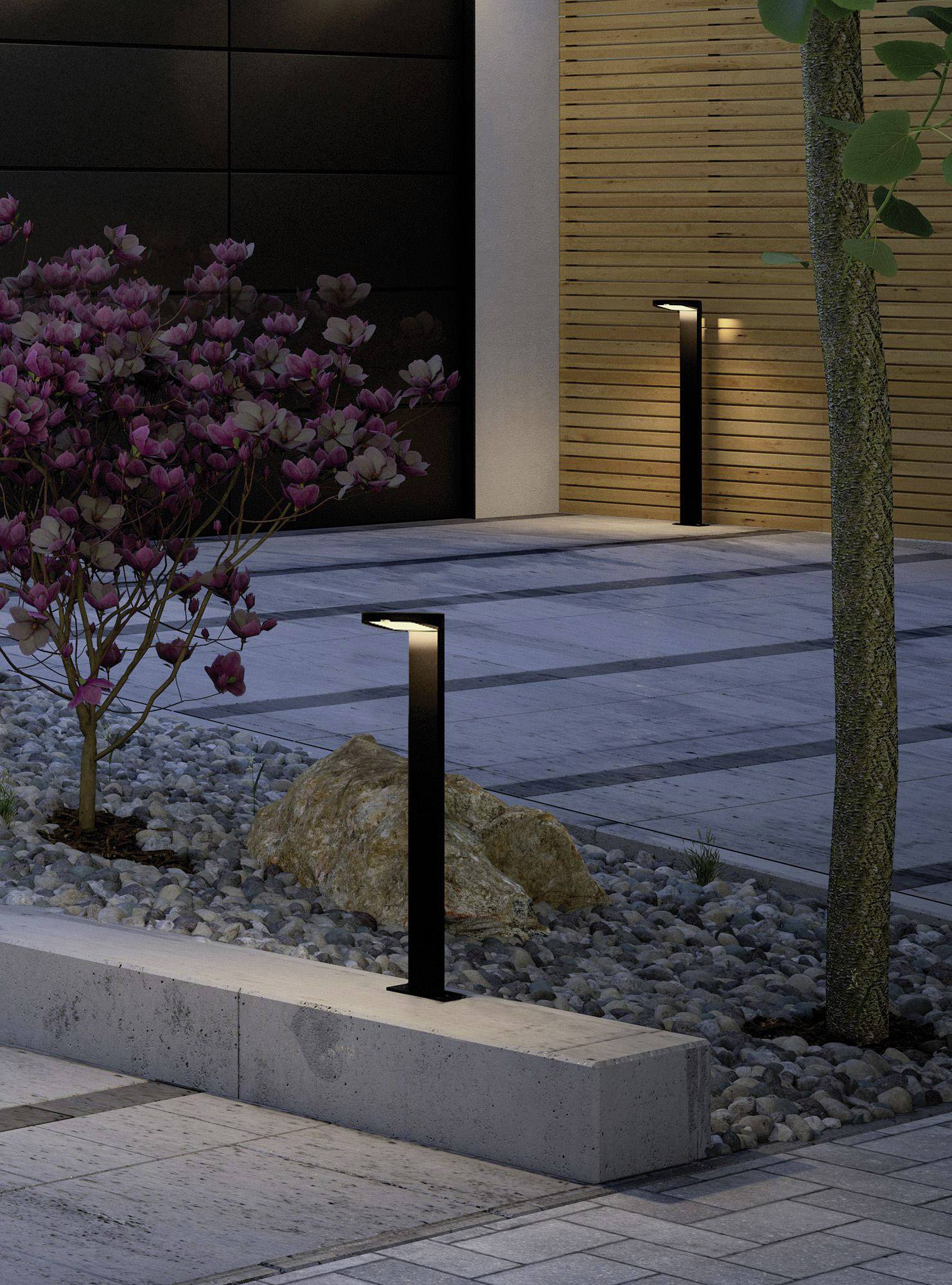 Nowoczesna przestrzeń zewnętrzna z roślinami, wielopoziomowymi kamieniami brukowanymi oraz stylowymi czarnymi latarniami wzdłuż ścieżki o zmierzchu.