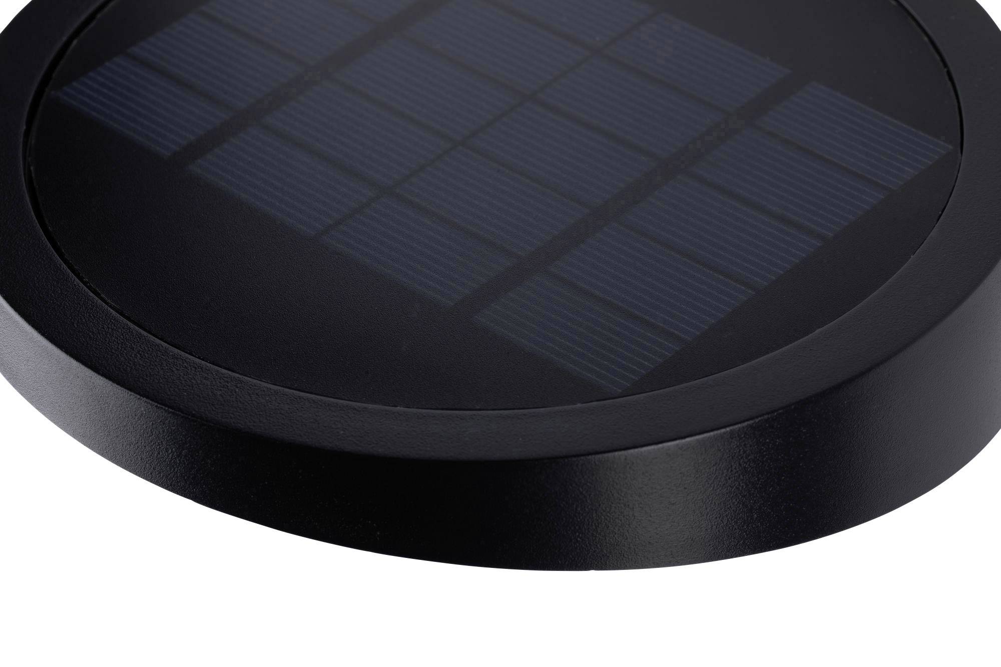 Okrągła, czarna latarnia solarna z wyraźnie widocznymi modułami słonecznymi na górnej powierzchni, prawdopodobnie przeznaczona do oświetlenia na zewnątrz.