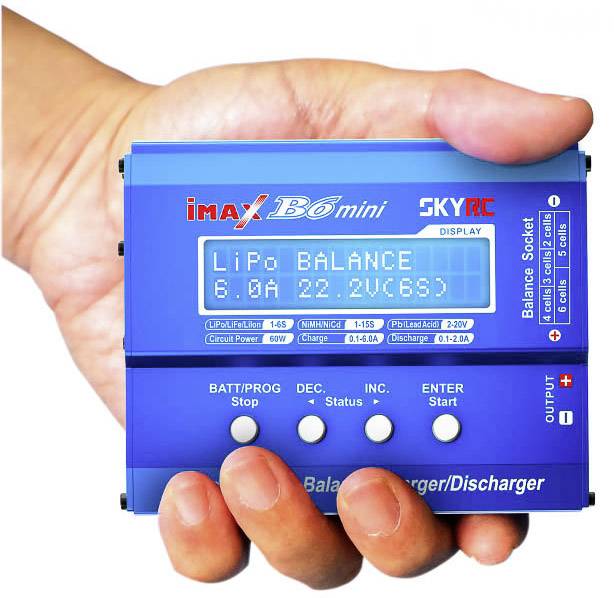 Ręka trzyma niebieskie ładowanie iMax B6 mini z wyświetlaczem: LiPo BALANCE, 6.0A, 22.2V (6S).