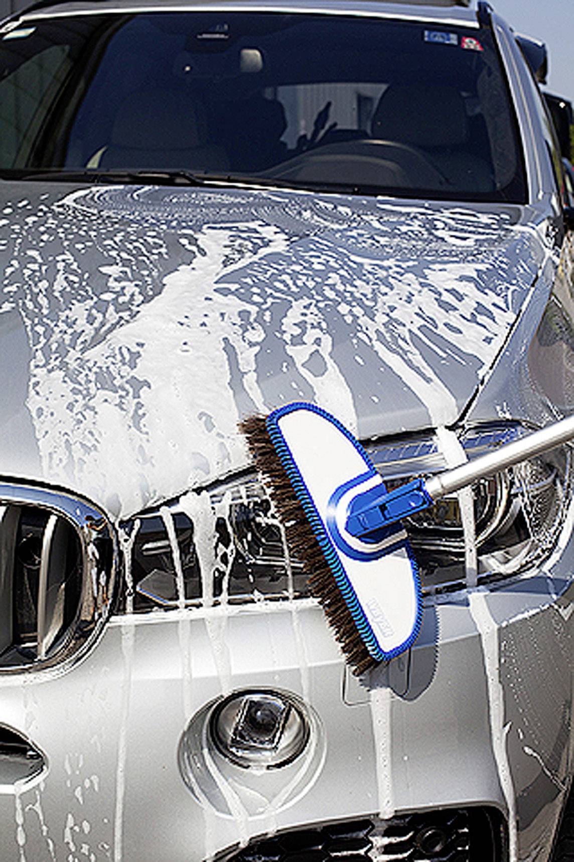 Samochód jest myty pianą i szczotką, widok z przodu.