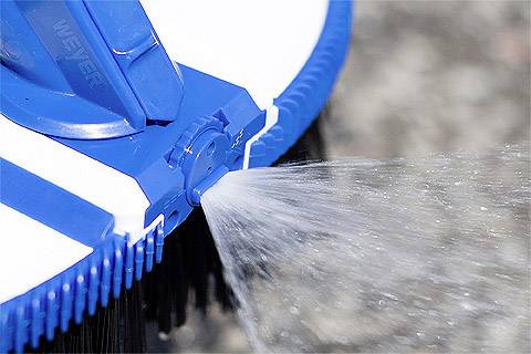 Niebieska szczotka wypuszcza strumień wody, czyszcząc powierzchnię.