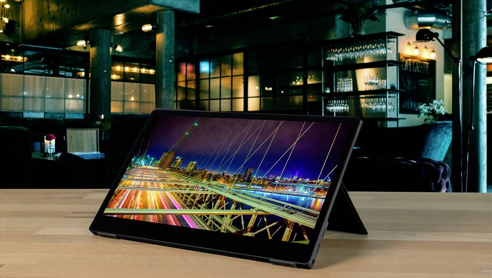 Tablet z obrazem nocnego widoku miasta w kawiarni; jasne światła na ulicy, nowoczesne otoczenie w tle.