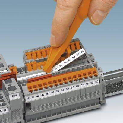 Ręka używa pomarańczowego narzędzia do podłączania przewodów w skrzynce rozdzielczej.