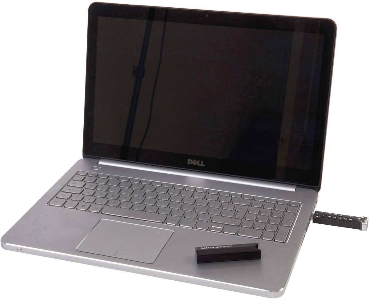 Otwarty laptop z czarnym ekranem, leżący na stole, z podłączonym urządzeniem USB po prawej stronie.