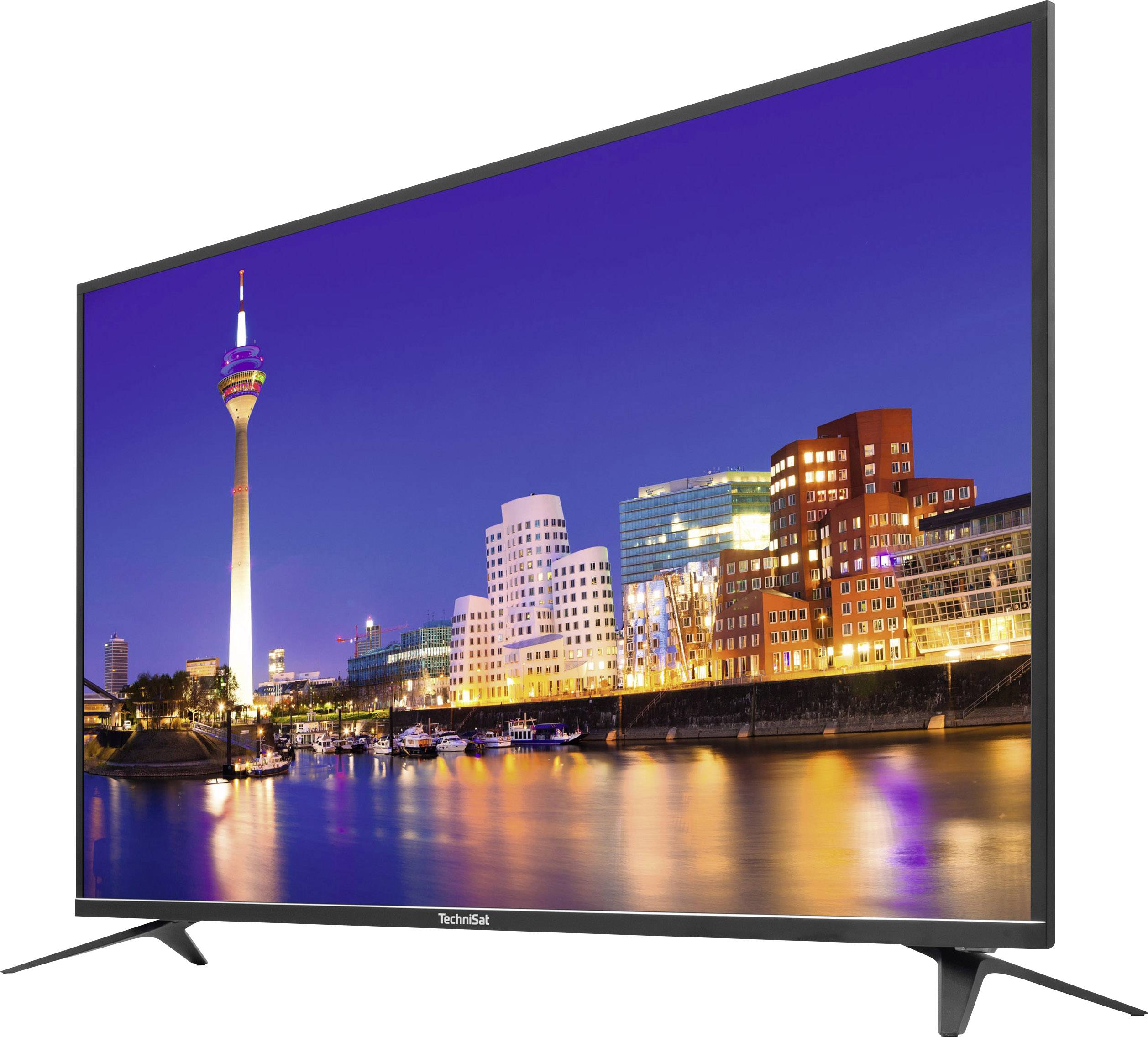 Telewizor przedstawia nocną panoramę Düsseldorfu, z podświetlonymi budynkami i wieżą telewizyjną nad brzegiem Renu.